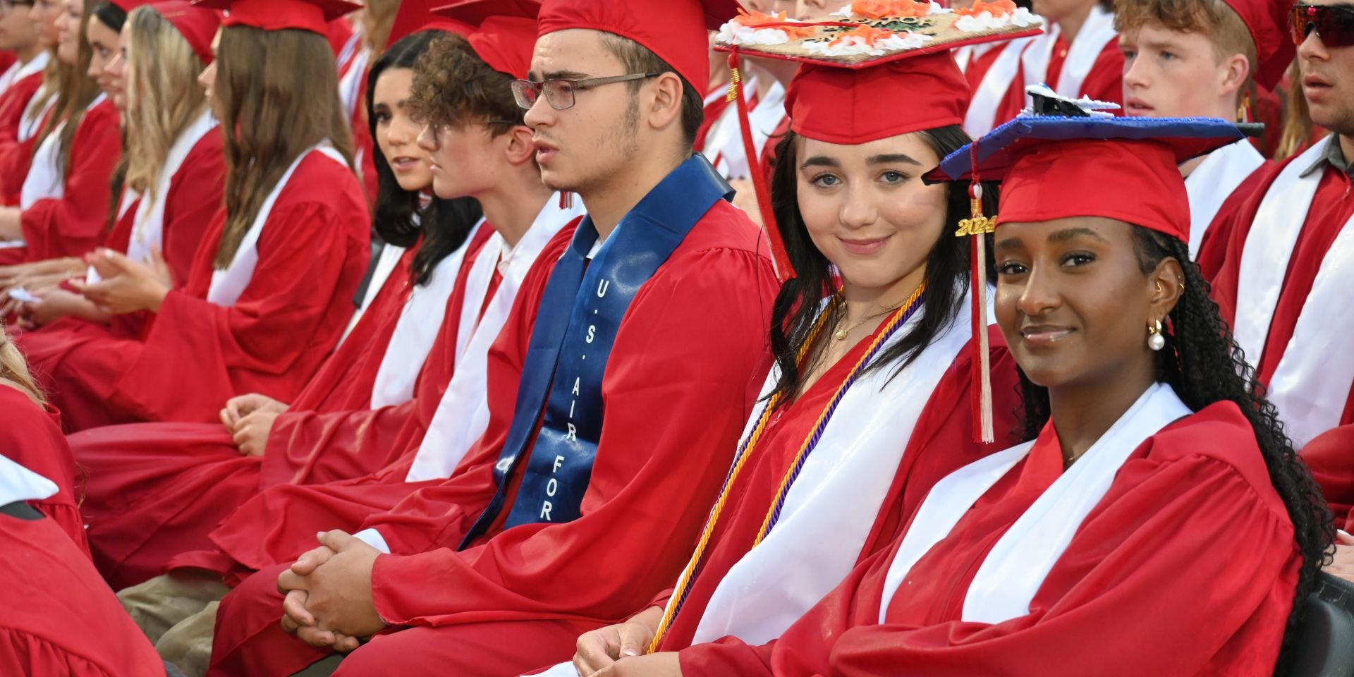 Two students dressed in graduation robes smile